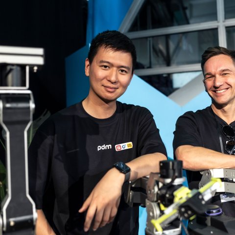 Yiyang Lu, Head of Research and Development bei pdm solutions, und Christian Baumert, CEO von pdm solutions, mit den Proof-of-Concept-Roboter-Modellen.